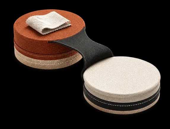 Clay and ivory discs linked by a leather strap, in the brand's S-curve